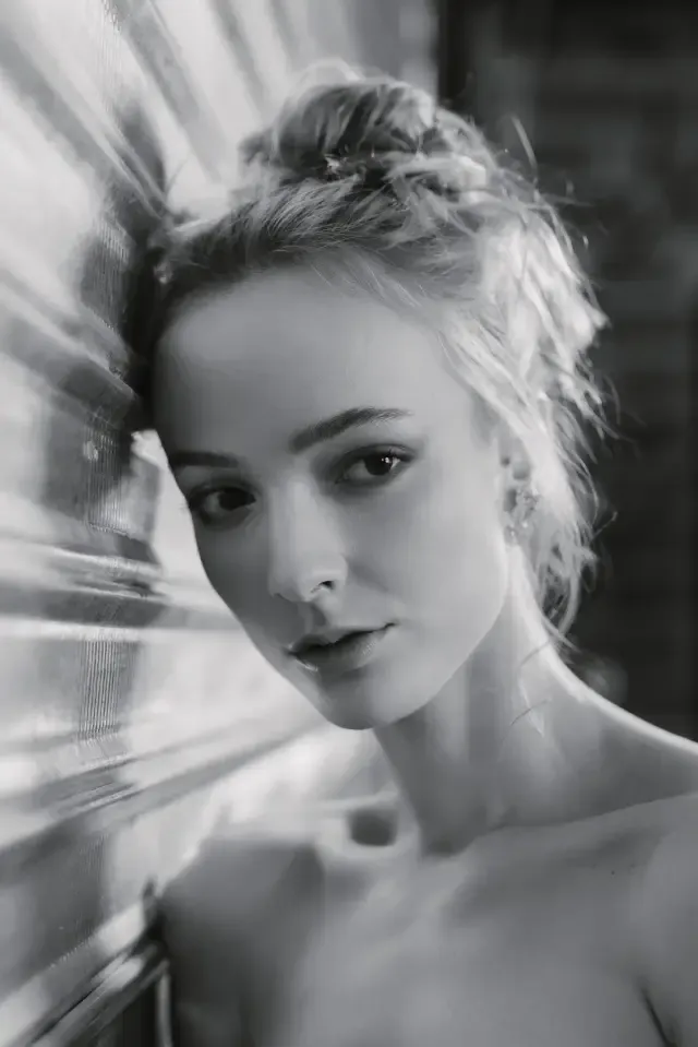 Retrato en blanco y negro de una mujer con el cabello recogido y reflejos de luz a un costado